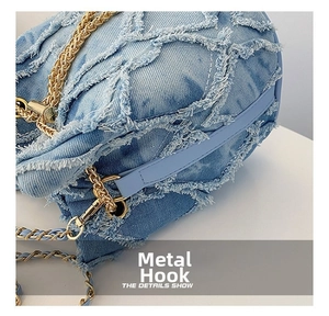 Close-up of light blue denim bag featuring frayed geometric texture and gold chain link