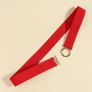 Detail of red elastic waist belt for women with golden round metal buckle over beige background
