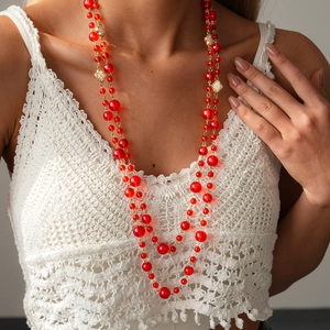 Detail of beaded red crystal layered necklace with clover charm on woven top