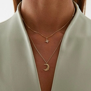 Close-up of a double-layered gold necklace with sparkling star and crescent moon pendants