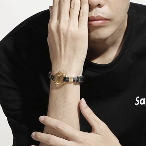 Gros plan d'un bracelet en cuir tressé noir pour homme avec un fermoir en U en métal doré
