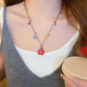 Gros plan du pendentif pomme en émail et perles colorées sur collier tissé