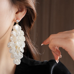 Dettaglio degli orecchini a petali bianchi stratificati con zircone indossati da una modella