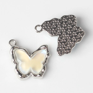 Detail of butterfly pendant showing pearly resin inlay and star-embossed metal back