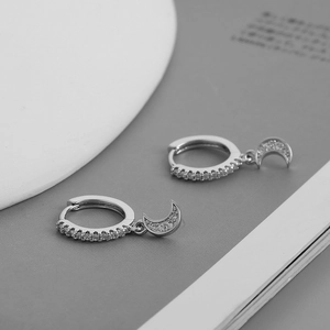 Macro detail of S925 silver hoop earrings featuring pavé cubic zirconia crescent moon charms
