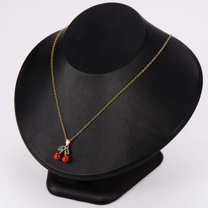 Golden chain necklace with red cherry pendant displayed on a professional black mannequin