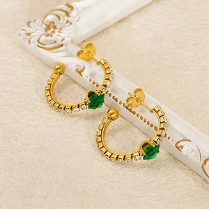 Detail view of vintage gold hoop earrings with square green gems and small zircons