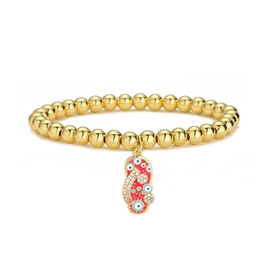 Close-up of 18K gold-plated beaded bracelet with a red enamel slipper and evil eye charm