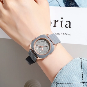 Close-up of a minimalist rose gold square watch with a sleek grey silicone strap on wrist