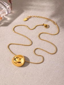 Close-up of polished 18k gold plated stainless steel bean pendant on a box chain