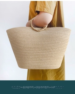 Detail of handwoven light khaki straw tote bag with round handles on a yellow dress