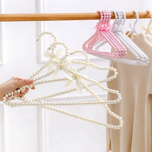 Elegant pearl clothes hanger with a pink ribbon bow hanging on a wooden rod