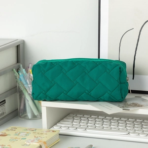 Close-up of emerald green quilted stationery bag with metal zipper and woven texture detail