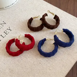 Three pairs of C-shaped hoop earrings with pleated fabric wrap in brown, red, and navy blue