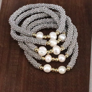 Detailed view of handmade stacked beaded bracelets with white pearls on wooden surface