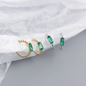 Detail of s925 silver ear cuffs with green emerald zircon and golden bead textures