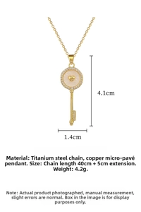 Detail view of gold key pendant with heart center and micro-pave crystals on titanium chain