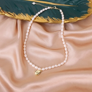 Detail of freshwater pearl necklace featuring a golden starburst teardrop pendant charm