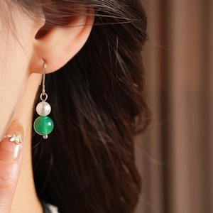 Primo piano di orecchini vintage in argento con perla bianca e grande perla in agata verde