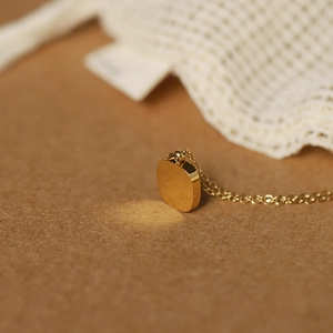Macro shot of a gold polished square pendant with shell texture on a fine chain