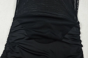 Detail of black mini dress featuring sheer mesh panel and ruched fabric texture