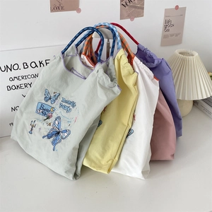 Close-up of embroidered butterfly totes in mint, yellow, white, pink and purple colors