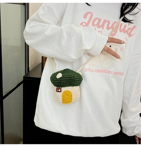Detail showing a mushroom-shaped knit crossbody bag with green top and white body