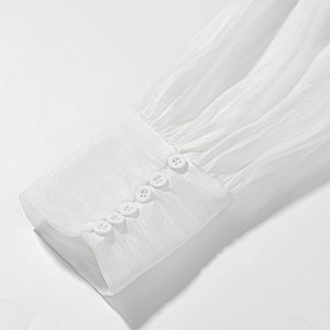 Detailed close-up of white pleated chiffon sleeves featuring elegant long buttoned cuffs