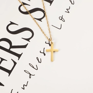 Detail shot of golden cross pendant necklace with classic O-chain on white background