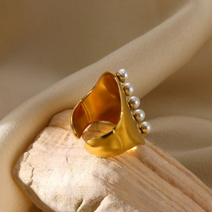 Detail of wide gold band ring with five white pearls set on a textured stone base