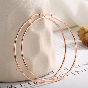 Detailed view of rose gold oversized hoop earrings with a metallic polished finish