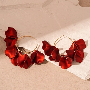 Macro detail of gold hoop earrings featuring elegant layered matte red acrylic flower petals
