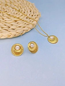 Detail of gold necklace and earring set featuring shell texture pendants and pearls