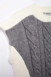 Close-up of grey cable knit texture with contrast white crew neck stitching details
