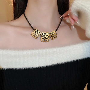 Detailansicht der Vintage Goldanhänger mit Leopardenmuster an einer schwarzen Lederkette