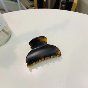 Detail view of a shell-shaped tortoiseshell plastic hair claw on a white table surface