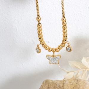 Golden titanium steel beaded bracelet with butterfly and round crystal charms in warm light