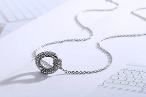 Macro shot of silver circular pendant with sparkling rhinestones on a fine steel chain