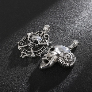 Gothic punk ram horn and skull pendants in aged stainless steel on dark texture