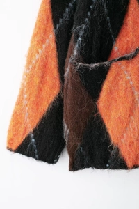 Gros plan des poignets en tricot avec motif losanges orange et noir et texture laineuse