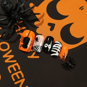 Halloween press-on nails featuring orange spider webs and spooky eye cartoon designs