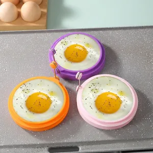 Three colorful silicone egg rings in purple, orange, and pink on a non-stick pan