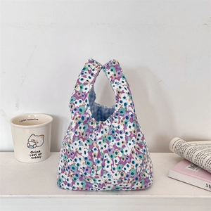 Detail of floral corduroy wrist bag with blue checkered lining on white surface