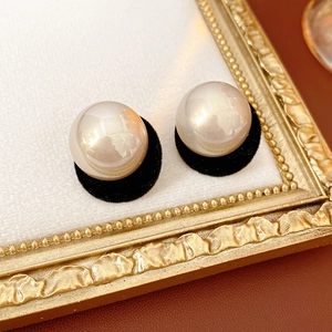 Detailed macro shot of vintage plush pearl earrings on a classic golden embossed frame