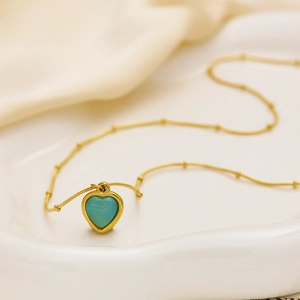 Close-up of heart-shaped blue opal pendant necklace on white ceramic and silk