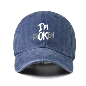 Blue washed denim baseball cap with I'M BROKEN text print and curved brim on white background