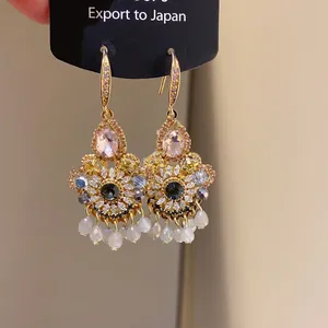 Macro shot of satin waterdrop earrings with pink oval stones and blue crystals