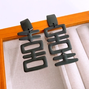 Macro shot of matte black Double Happiness character earrings on a velvet display tray