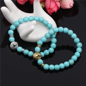 Beaded turquoise bracelets featuring gold and silver lion heads on a polished surface