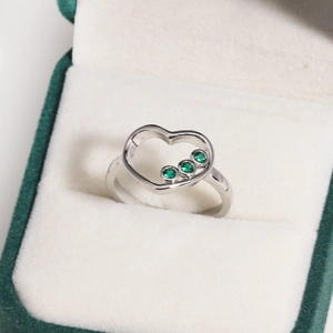 Détail de bague coeur plaqué or 14k avec zircons verts présentée dans son écrin cadeau